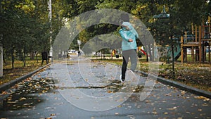 Girl play and jump in puddle in park after autumn rain. Fall rainy weather outdoors activity for young child. Kid