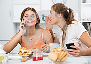 Girl is playfull talking by phone and her girlfriend is interesting it