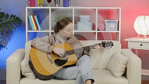 Girl playing acoustic guitar at home.