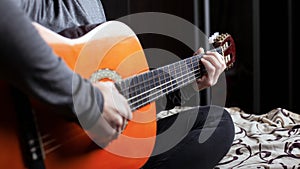 Girl playing an acoustic six-string guitar close-up. musical instrument lessons