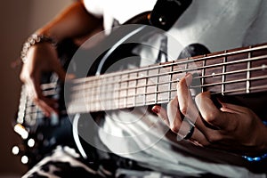 Girl playing Bass guitar indoor in dark room close up