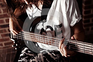 Girl playing Bass guitar indoor in dark room