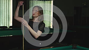 Girl playing billiard pool game is chalking her pool cue tip