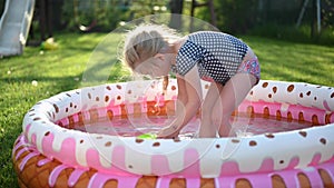 Girl playing in blow up pool in backyard in bright sunlight