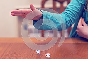 A girl playing a board game and rolls dice. Hand throws the dice on the background of colorful blurred fantasy Board games, gaming