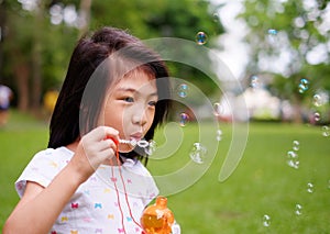 A girl playing with bubbles, blowing them into the air