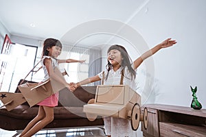 girl playing with cardboard toy airplane at home