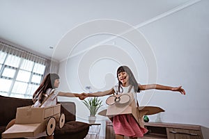 girl playing with cardboard toy airplane at home