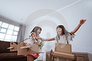 girl playing with cardboard toy airplane at home