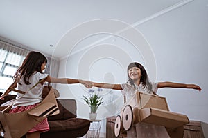 girl playing with cardboard toy airplane at home