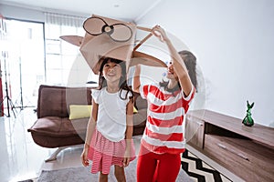 girl playing with cardboard toy airplane at home