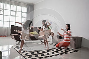 girl playing with cardboard toy airplane at home with mother