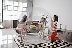 girl playing with cardboard toy airplane at home with mother