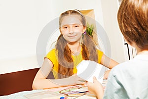 Girl playing cards sitting against her opponent