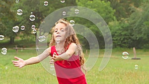 Girl playing catch soap bubbles on the garden. Slow motion. Close up