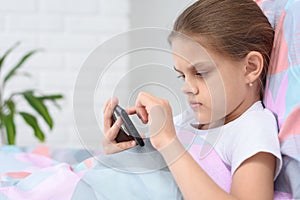Girl playing on a cell phone while lying in bed