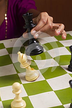 A girl playing chess game. Defeating the White bishop taking the Black Queen in her hand on chessboard