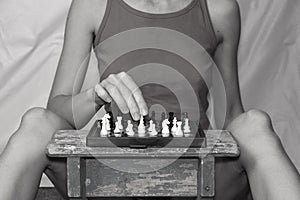 Girl playing chess at the table alone at home