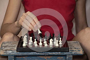 Girl playing chess at the table alone at home