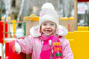 Girl playing on a children`s playground in winter