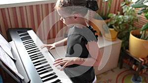 Girl playing classic digital piano during family home concert, emotional playing, side view
