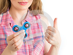 Girl playing with a colourful hand fidget spinner toy and showing thumbs up