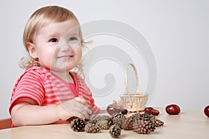 Girl playing with cones and chestnuts