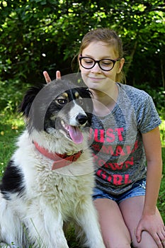 Girl playing with dog on grass. Teenager hugging Carpathian Shepherd Dog in the summer park. Friendship concept of man and animal