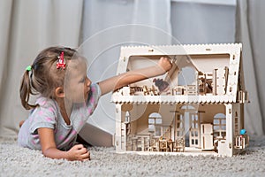 A girl playing with a dollhouse