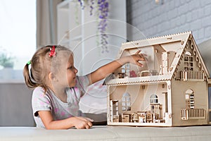 A girl playing with a dollhouse