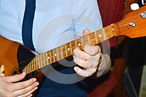 The girl is playing dombra and beating the chords on the guitar, close-up.