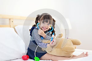 Girl playing education doctor and listening stethoscope on the bed.