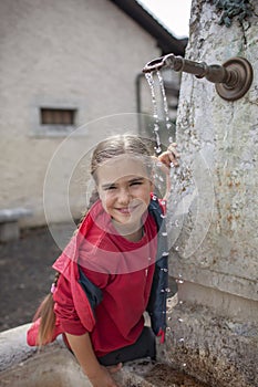 Girl playing with fountain water in the old European village
