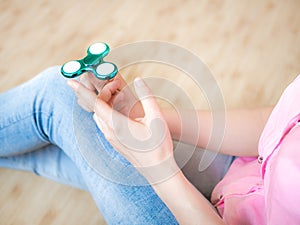 Girl playing with a glossy light colourful hand fidget spinner toy