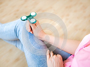 Girl playing with a glossy light colourful hand fidget spinner toy