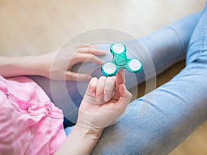 Girl playing with a glossy light colourful hand fidget spinner toy