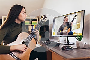 Girl playing guitar with computer, learn to play with an online course