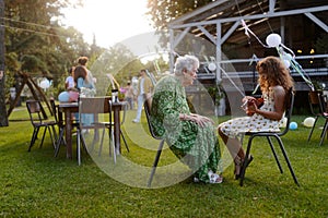 Girl playing on guitar for her grandmother at garden party. Love and closeness between grandparent and grandchild. photo