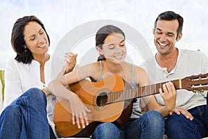 Girl playing guitar with her parents