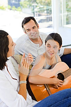 Girl playing guitar with her parents