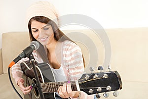 Girl playing guitar and singing on microphone