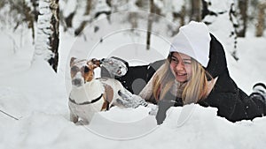 A girl playing with her Jack Russell Terrier dog in the snow.