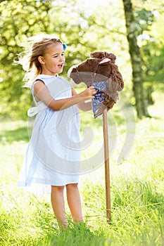 Girl Playing With Hobby Horse In Summer Field