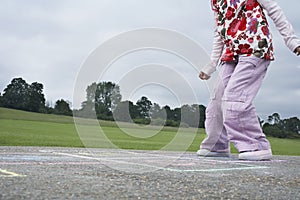 Girl Playing Hop-Scotch In Playground