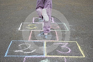 Girl Playing Hop-Scotch In Playground photo