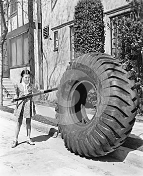 Girl playing with a huge tire and stick