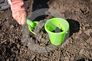 Girl playing in the mud with green toys