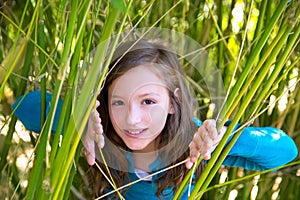 Girl playing in nature peeping from green canes