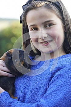 Girl Playing With Pet Guinea Pig Outdoors In Garden