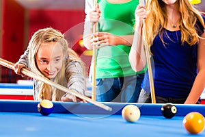 Girl playing pool billiard with family